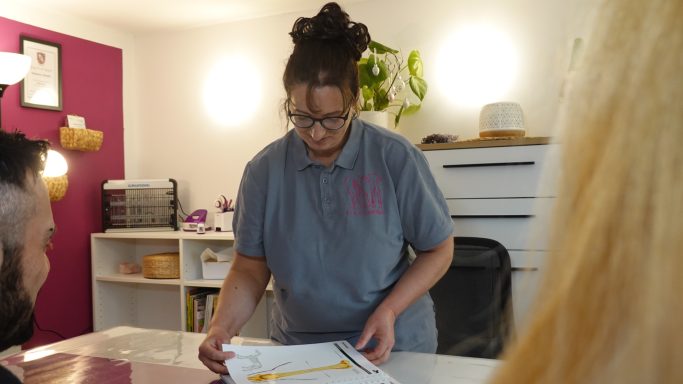 Frau mit Brille, die Unterlagen an einem Tisch organisiert, Blick auf die andere Person.